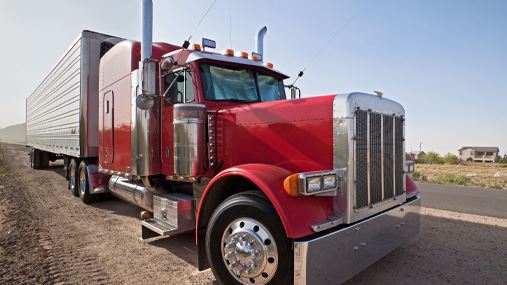 Red semi truck with trailer driving down the highway